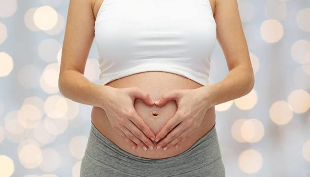 Pregnant woman making a heart with her hands on her belly