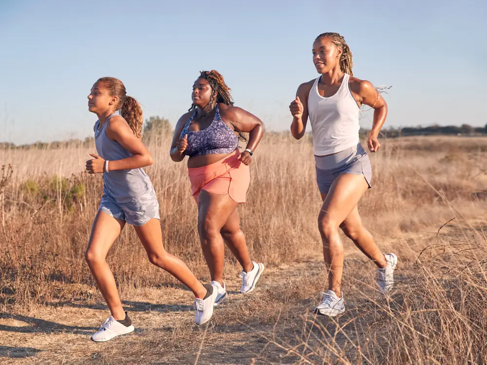 Three women running in the sunny trails