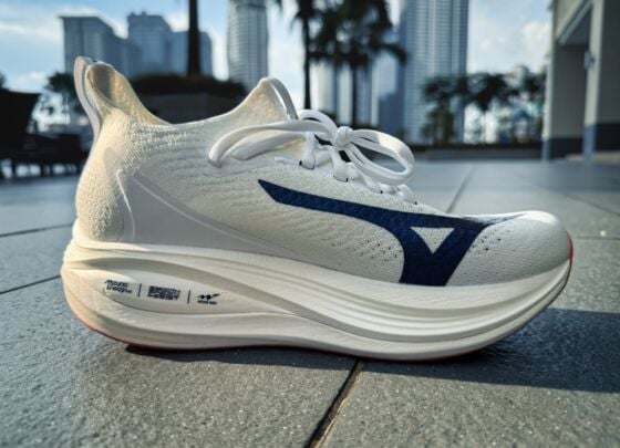 A pair of white Mizuno Neo Vista 2 running shoes with thick, cushioned soles and navy blue accents, placed side by side on a tiled floor in bright natural light, ready for your next review.